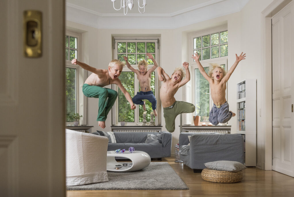 Boys in living room jumping in mid air