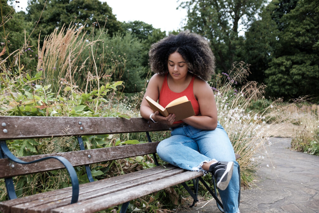 Woman reading book on a bench in the park