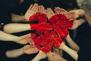 Multiple hands painted red joining together to create a heart shape